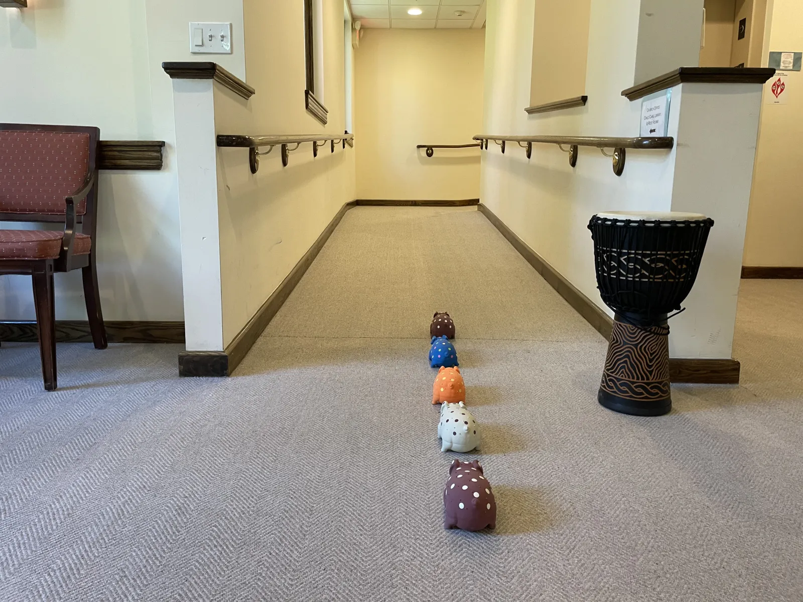 Colorful pig figures leading toward a drum and a wide hallway with handrails